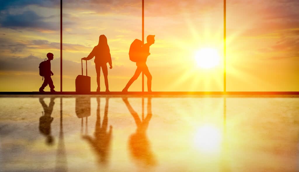 Family silhouette goes on trip. happy family goes on trip for summer vacation. Travelers waiting plane in airport at sunset interior with large windows.